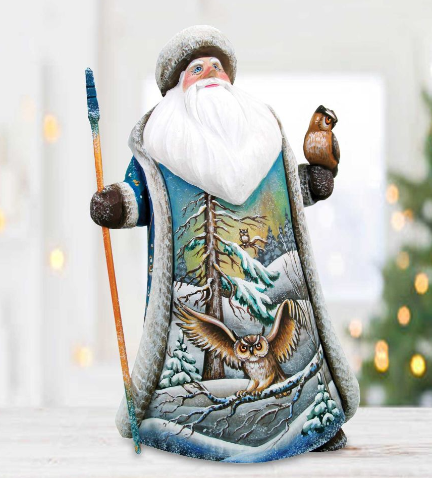 A figurine of Santa Claus holding a bird and a stick, with a snowy landscape and trees in the background.