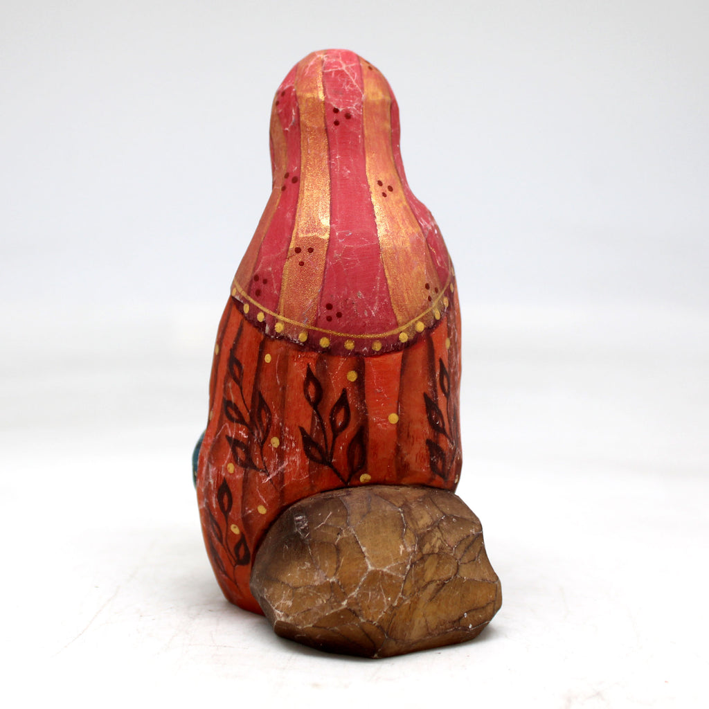a red and gold vase sitting on top of a rock