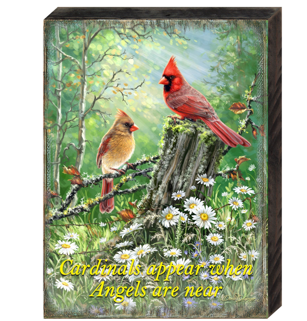 two red cardinals perched on a tree stump in a lush, green forest.