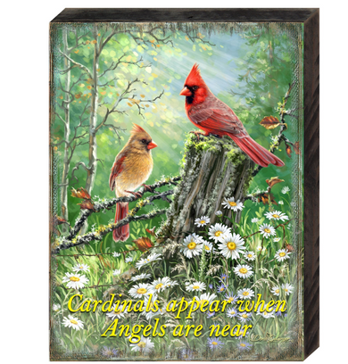 two red cardinals perched on a tree stump in a lush, green forest.