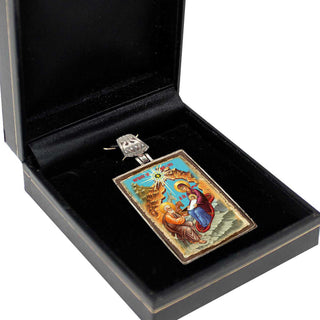 A black jewelry box containing a decorative pendant with an ornate design.