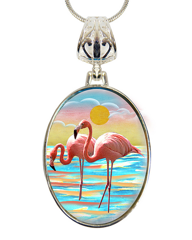A pendant necklace with a circular design featuring two pink flamingos standing on a beach at sunset.