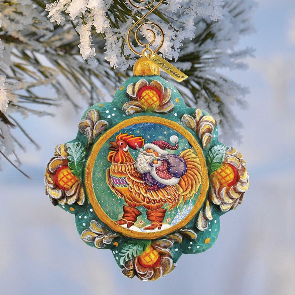 A colorful ornament featuring a rooster and snowflakes hanging from a tree branch.
