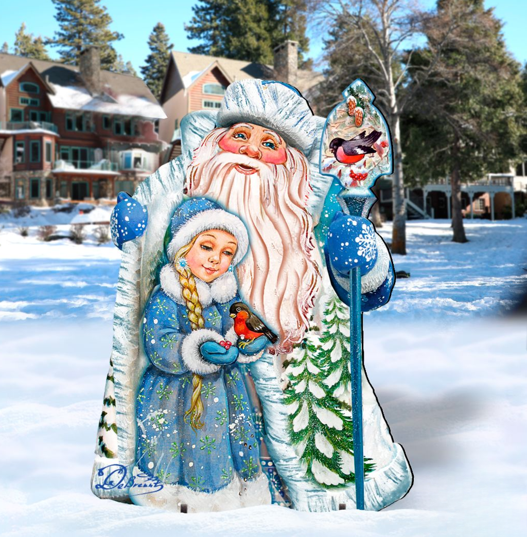 A large, colorful cardboard cutout of Santa Claus holding a young girl in a blue dress, with snow-covered trees in the background.