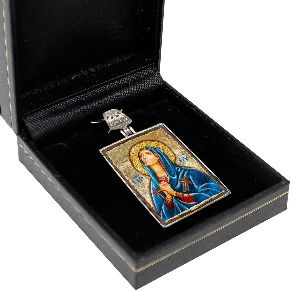 A pendant in a black box, featuring a religious icon of a woman in blue robes.