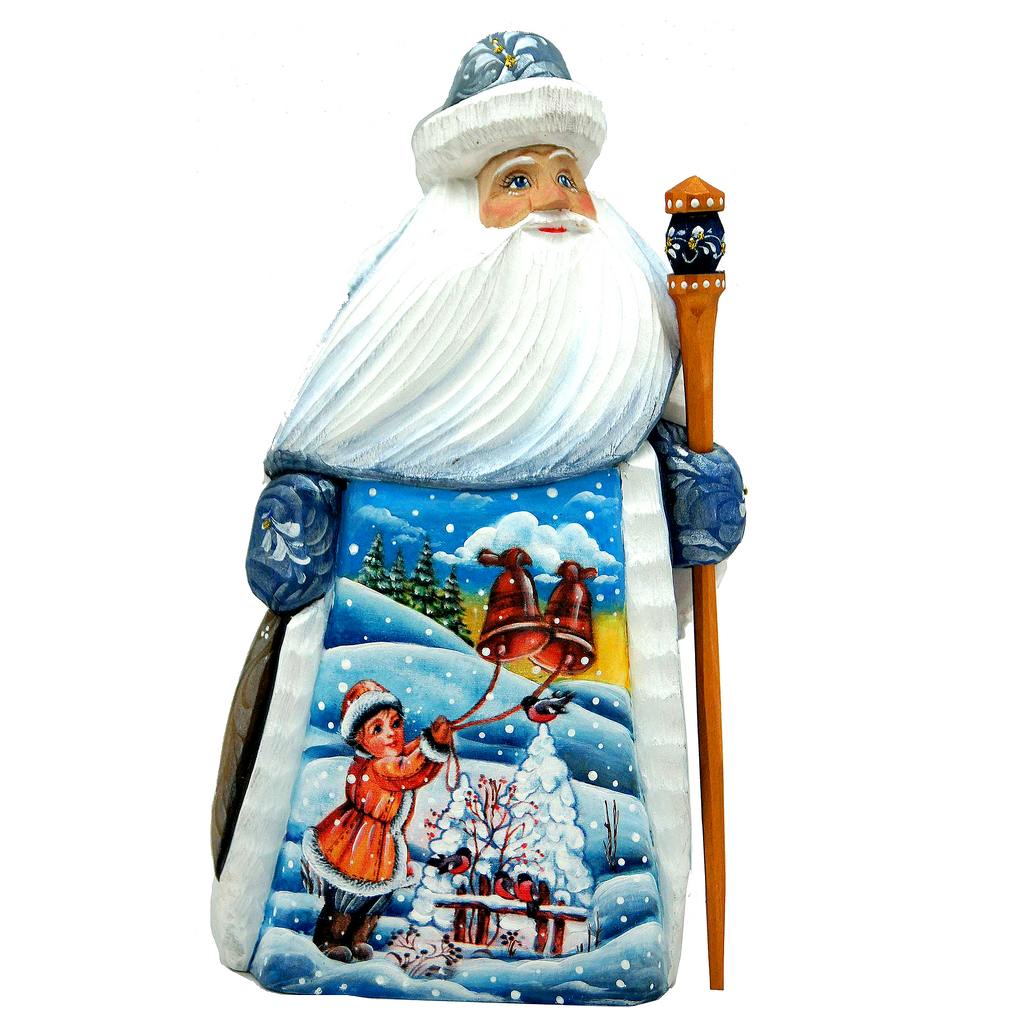A carved wooden Santa Claus figure with a white beard and hat, holding a bell and a lantern, set against a snowy winter landscape with a child.