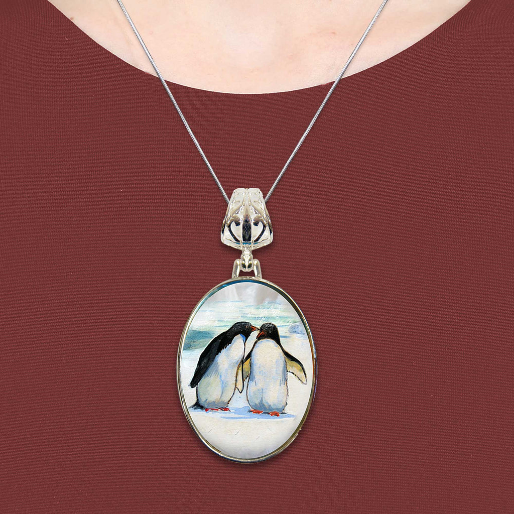A necklace with a pendant featuring a painting of two penguins.