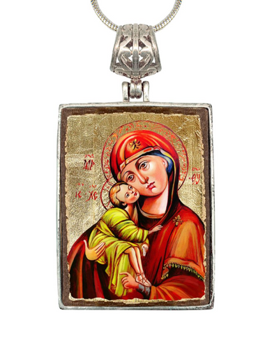 a religious icon of the Virgin Mary holding the baby Jesus, with a halo around her head and a red robe.