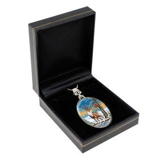 A pendant in a black jewelry box, featuring a deer and a snowy landscape.