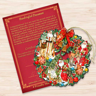 a handmade ornament with a wreath and various Christmas-themed decorations, including Santa Claus and other holiday characters. The ornament is placed on a wooden surface next to a red card with text and a certificate.