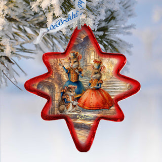 A red star-shaped ornament with a painting of three mice dressed in costumes, set against a snowy background.