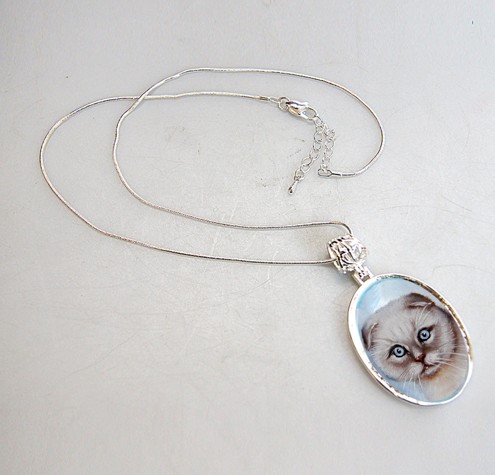 A silver necklace with a pendant featuring a close-up image of a cat's face.