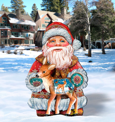A large cardboard cutout of Santa Claus holding a reindeer stands in a snowy landscape with houses and trees in the background.