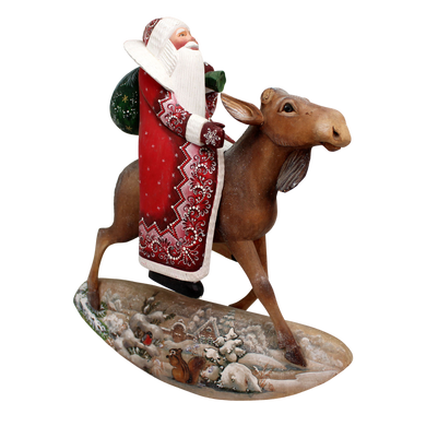 A figurine of Santa Claus riding a moose on a snowy landscape.