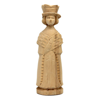 A wooden sculpture of a woman wearing a hat and a long dress, standing upright and facing forward.