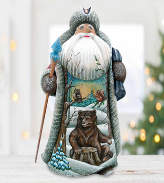 A wooden Santa Claus figurine with a detailed winter scene depicting a bear, a tree, and other wildlife elements.