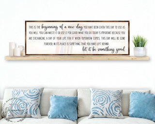 a framed inspirational quote on a wall above a couch with blue throw pillows.