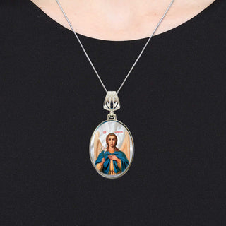 A silver necklace with a pendant featuring a portrait of a person.