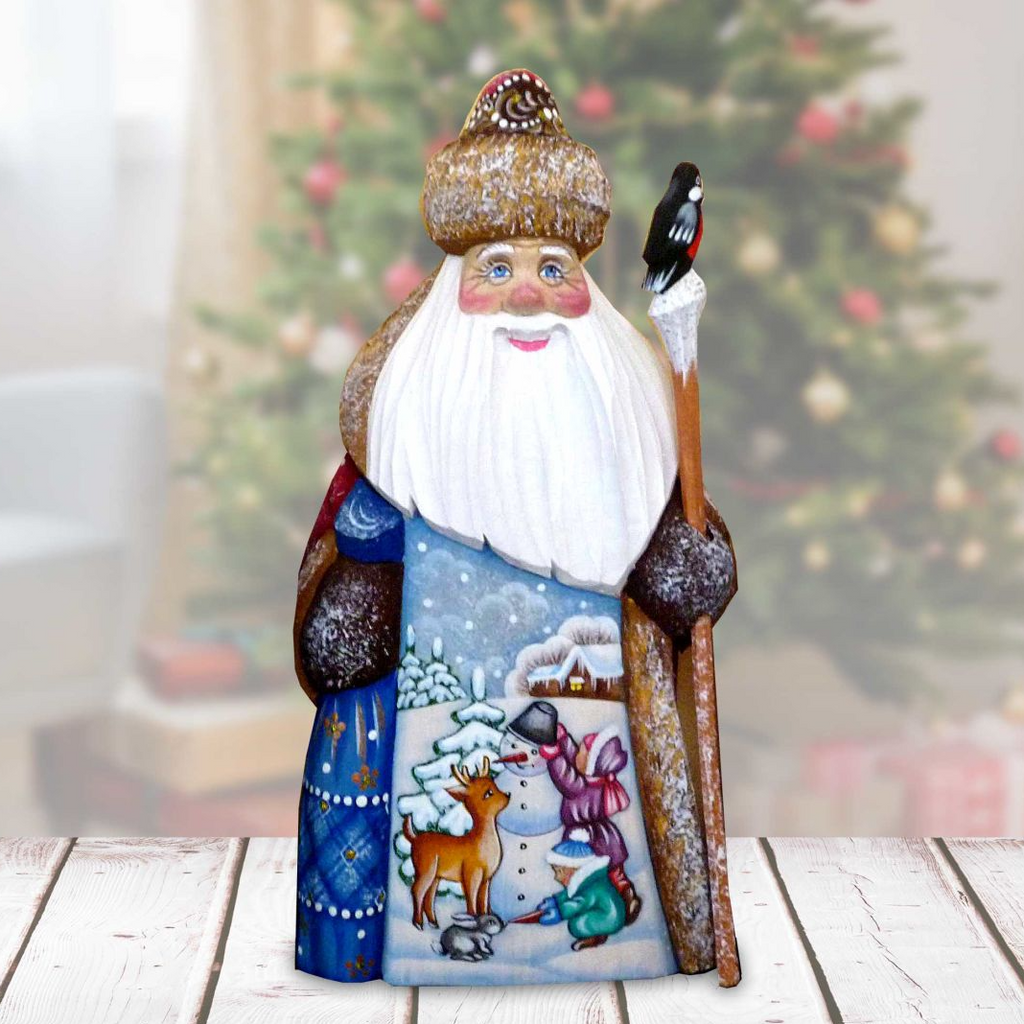 A hand-painted Christmas ornament depicting Santa Claus holding a reindeer and a bird, with a snowy winter landscape and a castle in the background.