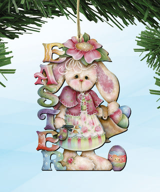A colorful Easter ornament featuring a bunny wearing a pink dress and holding a flower, with the word 