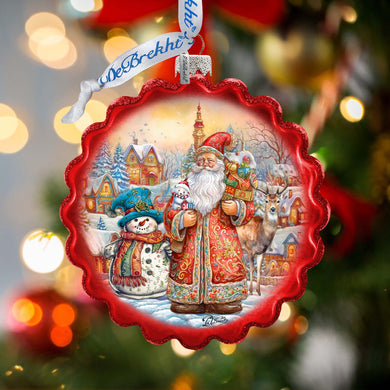 A red ornament with a winter scene featuring Santa Claus, a snowman, and reindeer, set against a snowy village backdrop.