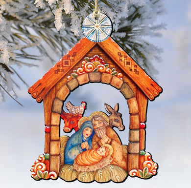 A wooden nativity scene ornament depicting the Holy Family of Jesus, Mary, and Joseph, with a rooster, a cow, and a baby lamb, is hanging from a tree branch.
