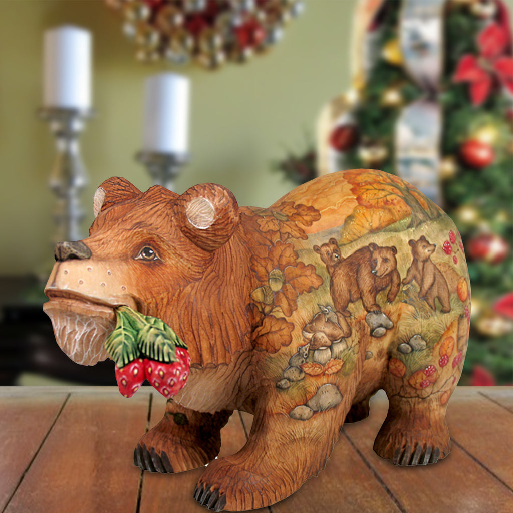 A wooden bear figurine with a painted design of bears and berries on its body, sitting on a wooden surface.