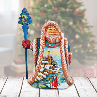 A wooden sculpture of Santa Claus holding a blue staff and a Christmas tree in the background.