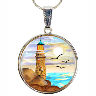 A round pendant necklace with a lighthouse and seagulls in the background, set against a colorful sky and ocean.