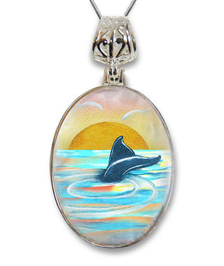 A pendant necklace with a glass pendant featuring a painting of a dolphin swimming in the ocean at sunset.