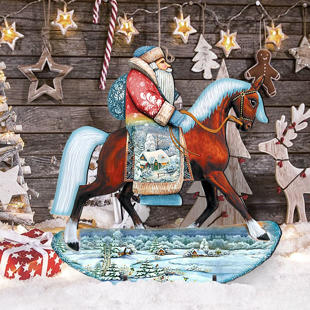 A wooden statue of Santa Claus riding a horse, with a snowy landscape and Christmas decorations in the background.