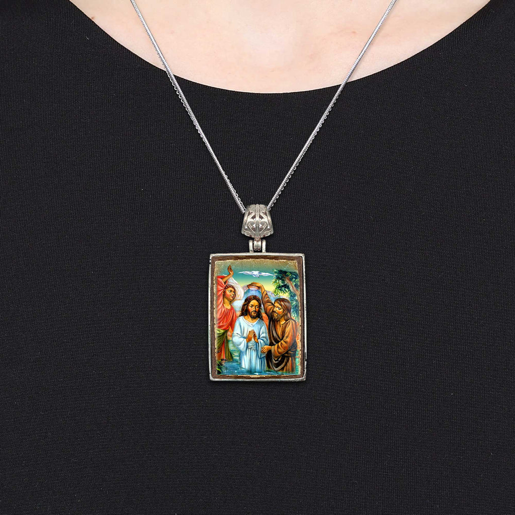 A silver pendant necklace with a rectangular pendant featuring religious imagery.