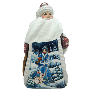 A carved wooden Santa Claus figure with a blue and white winter scene on its bag.