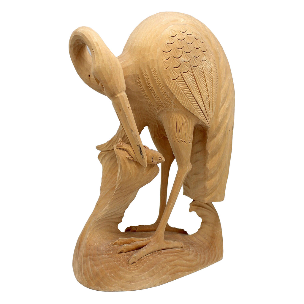 A wooden sculpture of a bird, possibly a crane, with intricate carvings and details.