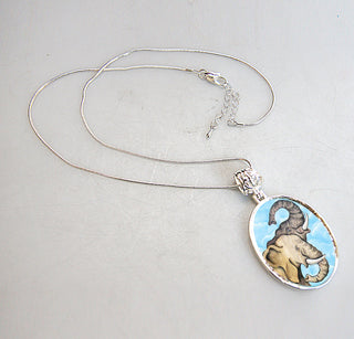 A silver necklace with a pendant featuring an elephant design.