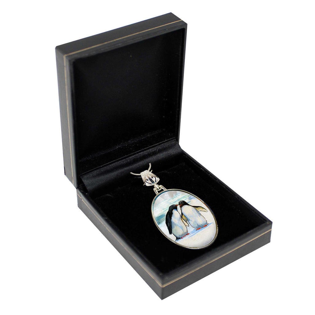 A pendant with a penguin image is displayed in a black jewelry box.