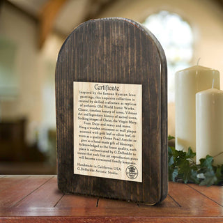 A wooden plaque with text on it, placed on a wooden surface with some greenery in the background.