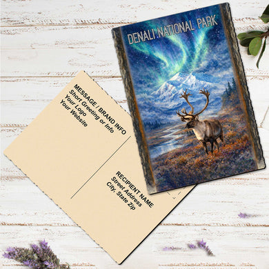 a postcard with a painting of a reindeer in front of a scenic landscape, including mountains and a lake, with a message for sending a greeting or information.