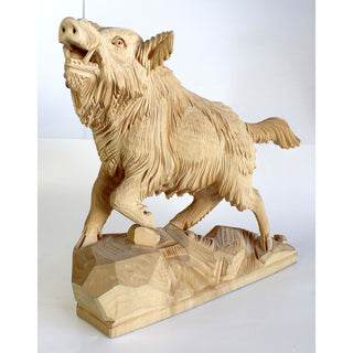 A wooden sculpture of a wild boar in mid-stride, with its mouth open and tail swishing, is depicted on a wooden base.