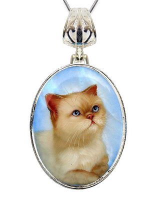 A silver pendant necklace with a round oval-shaped frame containing a close-up image of a cat with blue eyes and a pink nose.
