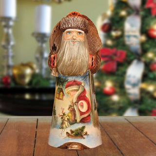 A wooden Santa Claus figurine with a detailed design, including a beard, hat, and a small Christmas tree, is displayed on a wooden surface.