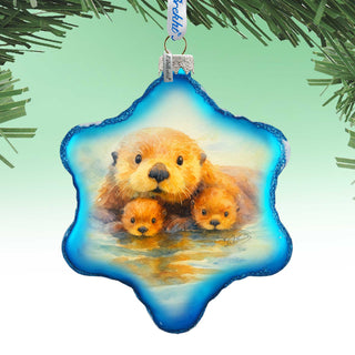 A blue star-shaped ornament with a painting of three otters swimming in a body of water.
