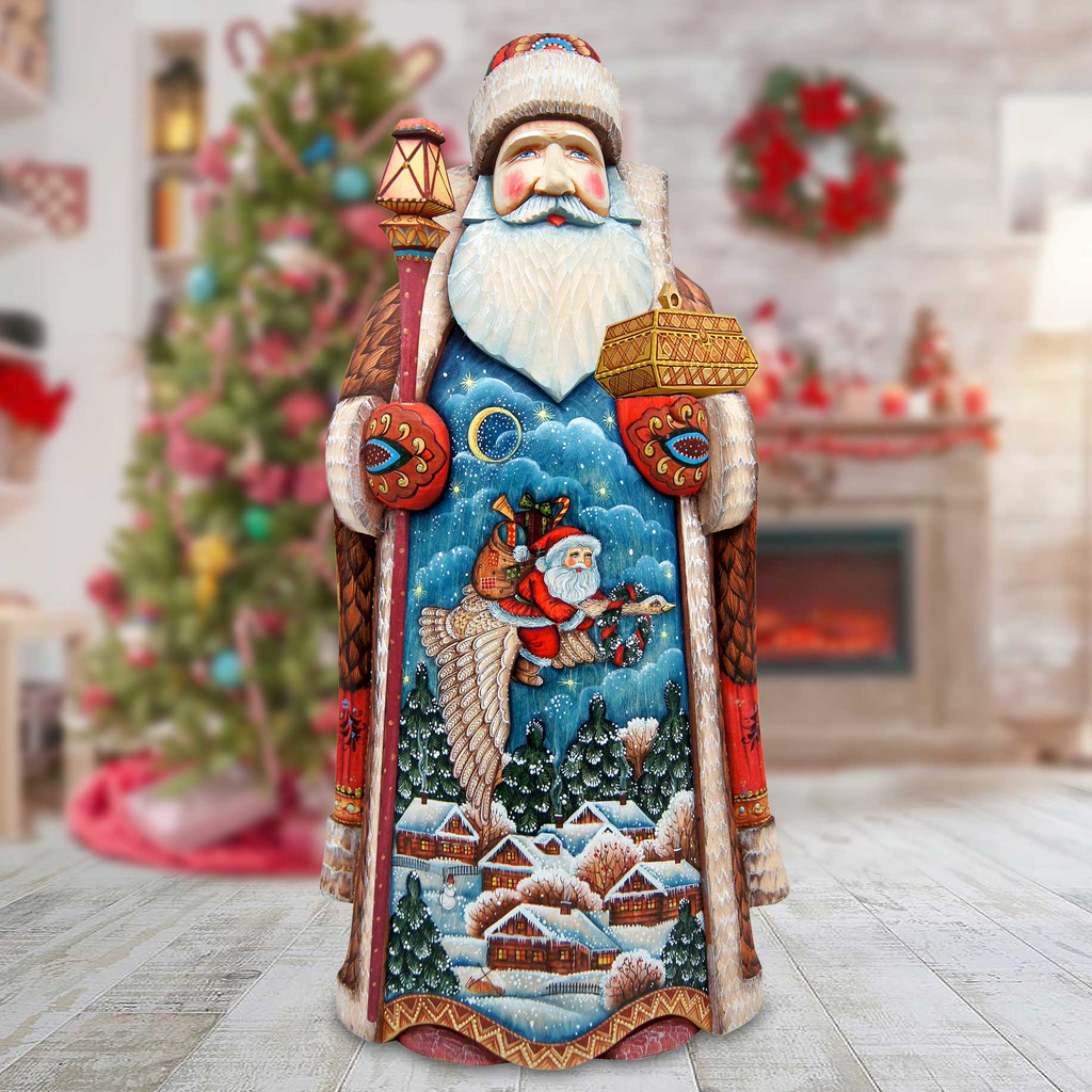A wooden Santa Claus figurine stands in a room decorated for Christmas, with a Christmas tree and wreath visible in the background.