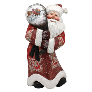 A figurine of Santa Claus holding a large bag with a picture of reindeer on it.