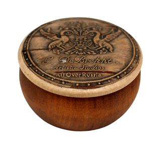 A wooden bowl with a decorative lid featuring a crest and text.