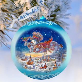 A blue Christmas ornament with a snowman and a bird flying above a snowy village scene.