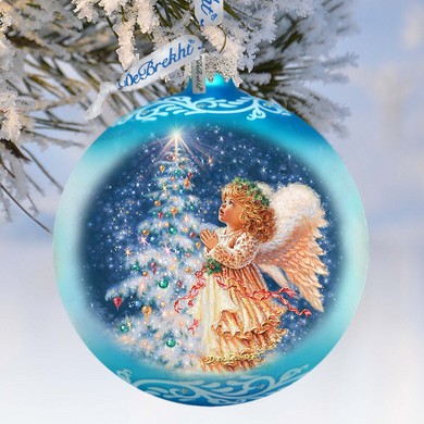 A blue Christmas ornament with a painting of an angel in a golden dress and white wings, gazing up at a decorated Christmas tree.
