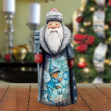 A figurine of Santa Claus holding a snow globe and a lantern, with a snowy background and a blurred Christmas tree in the background.
