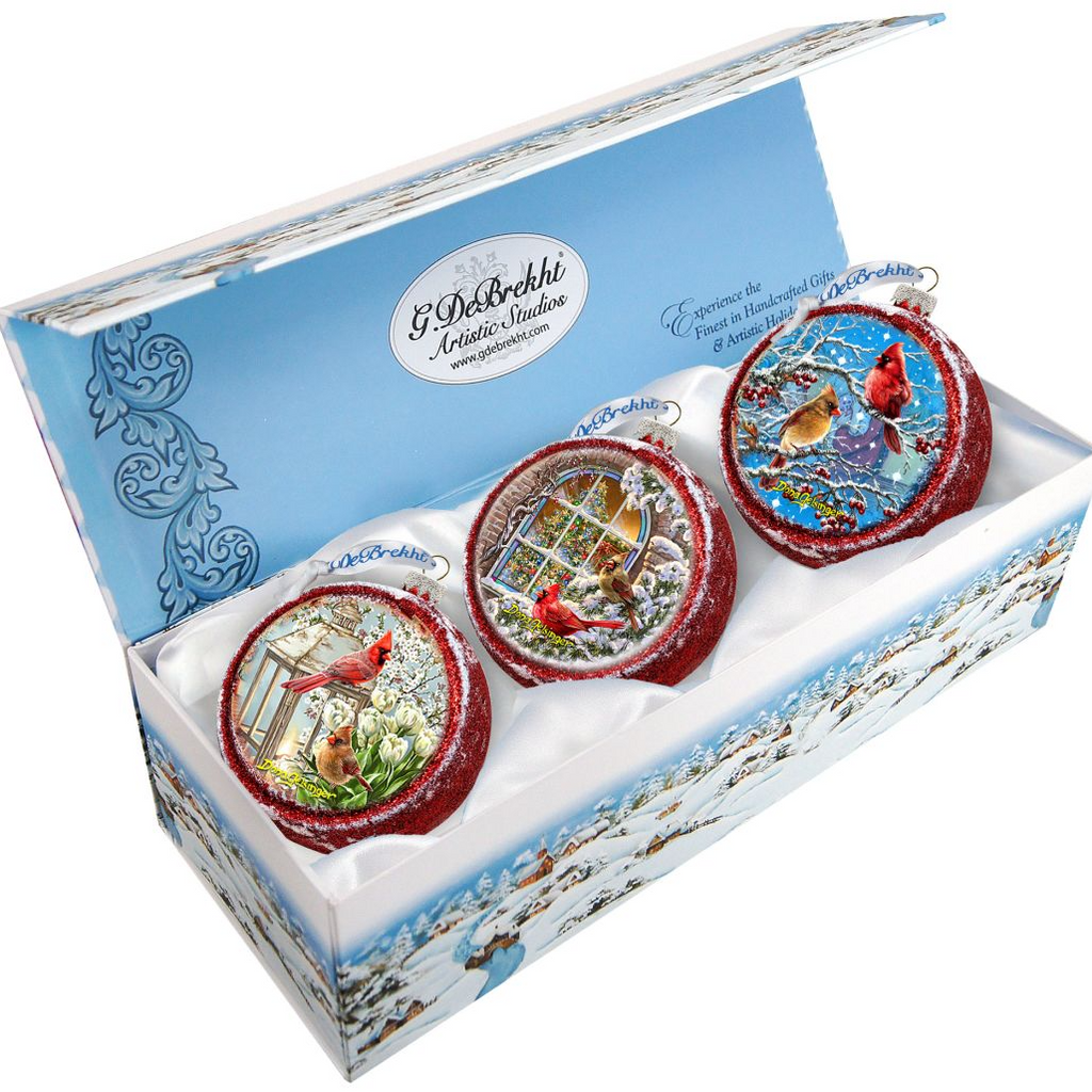 A set of three decorative Christmas ornaments in a box, each featuring a different scene with birds.