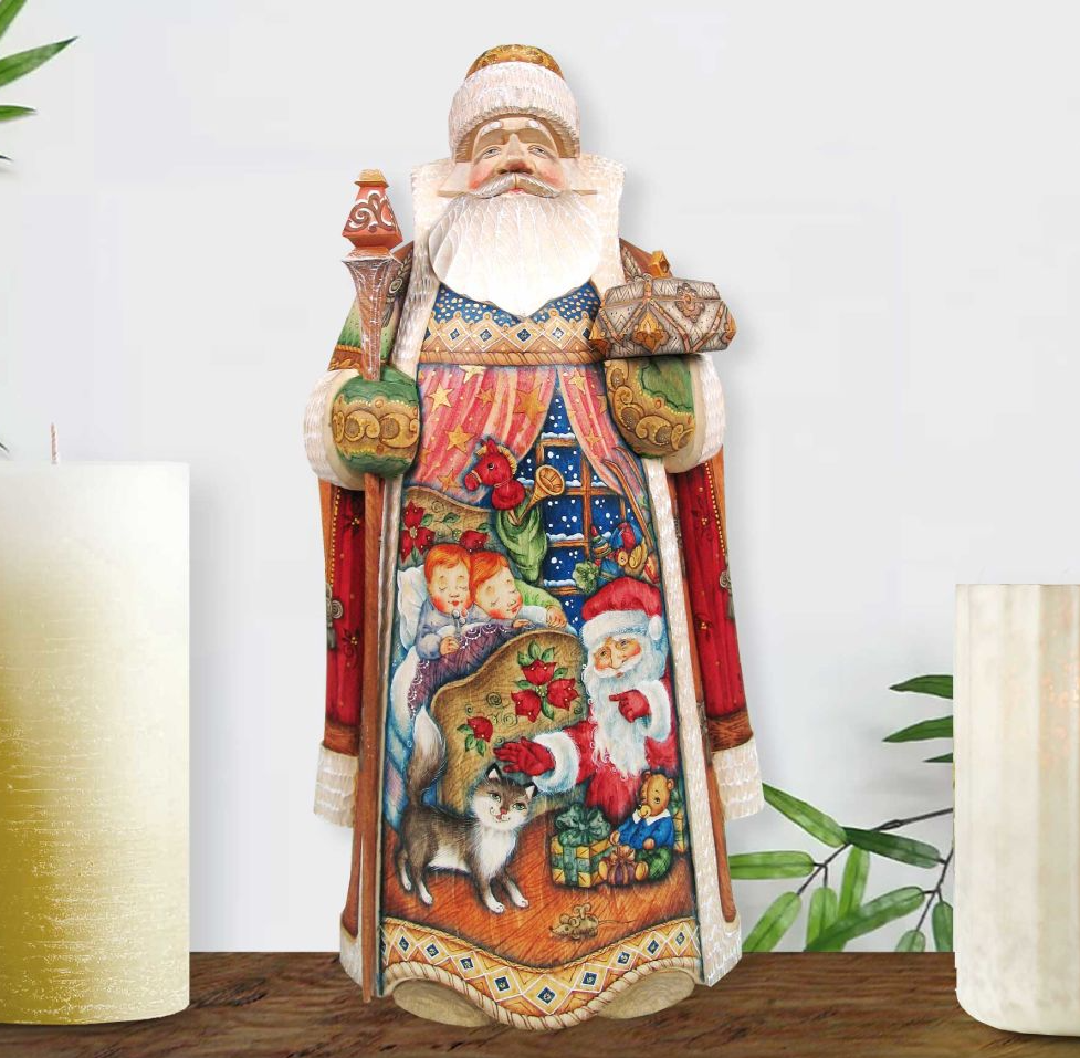 A colorful and intricately designed wooden Santa Claus figurine, adorned with various holiday-themed elements such as flowers, presents, and a cat, stands on a wooden surface.